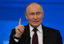 Man in suit gestures with raised index finger