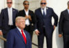 Man in blue suit with people in background standing