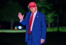 Man in suit wearing red hat outside at night