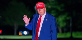 Man in suit wearing red hat outside at night