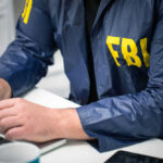 Person in FBI jacket using a laptop