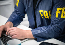 Person in FBI jacket using a laptop