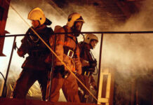 Firefighters in protective gear navigating through smoke