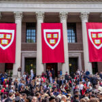 Harvard graduation ceremony with banners and crowd outside