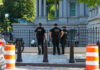 Three police officers in dark uniforms standing outside building