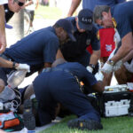 Emergency responders assisting person on grass lawn