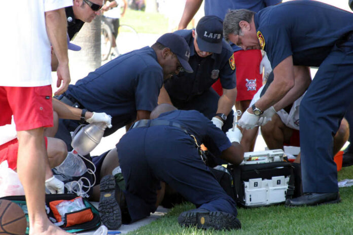 5883148 Emergency responders assisting person on grass lawn
