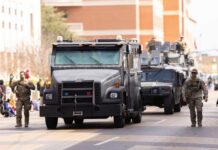 Military vehicles and personnel in a parade on a city street