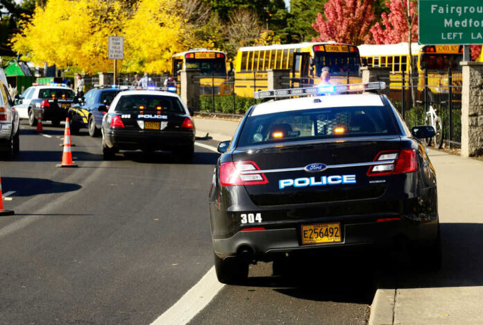 Police cars and school buses on roadside with cones