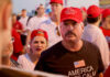 Man wearing red hat in crowded outdoor gathering