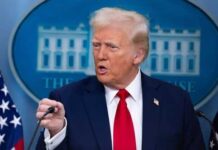 Nuclear Claims SPARK Chaos – MAGA vs. Intel Showdown A man in a suit speaking at a press conference with a serious expression