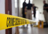 Fatal Mistake: Wrong House, Deadly Consequences Yellow crime scene tape with blurred figures in the background