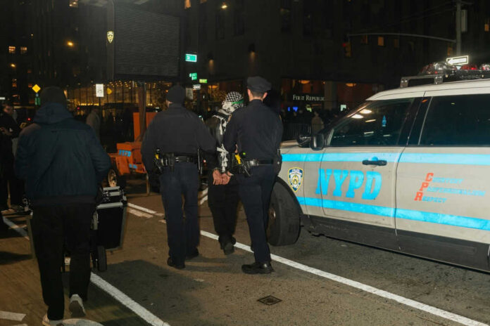 Police officers detain a person near NYPD vehicle