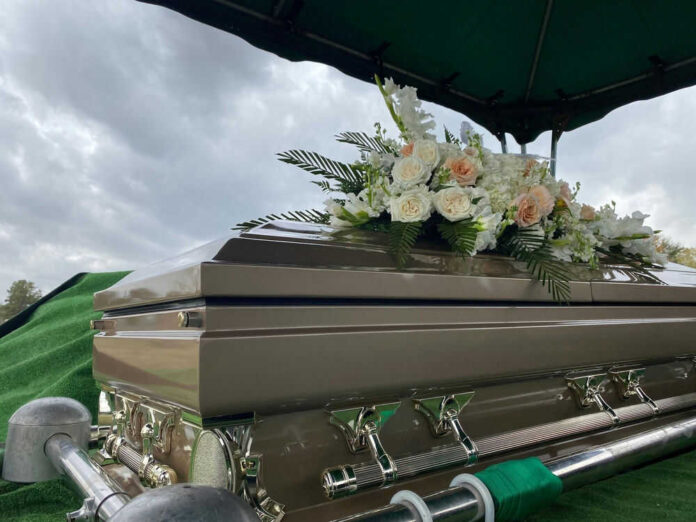 Casket with flowers under cloudy sky at funeral