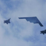 Five military aircraft flying in formation under clouds