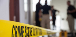 Yellow crime scene tape with blurred figures in the background